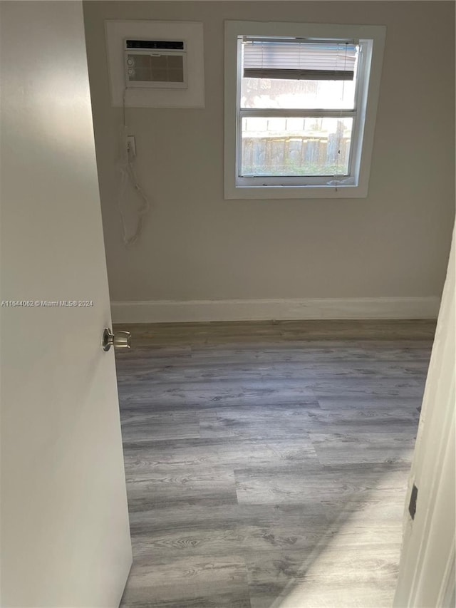 unfurnished room featuring light wood-type flooring and a wall mounted air conditioner