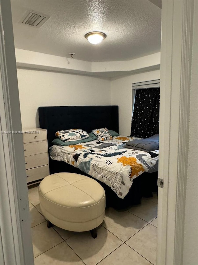 bedroom featuring light tile patterned flooring and a textured ceiling