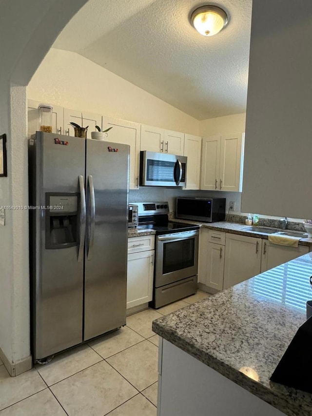 kitchen with white cabinets, sink, lofted ceiling, and stainless steel appliances