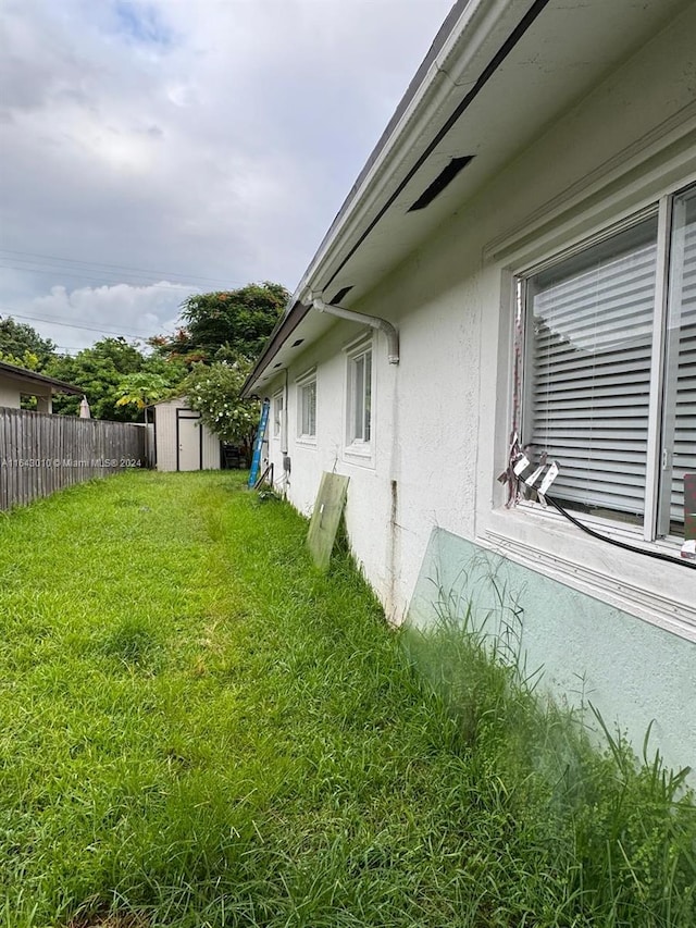 view of home's exterior with a storage unit and a yard