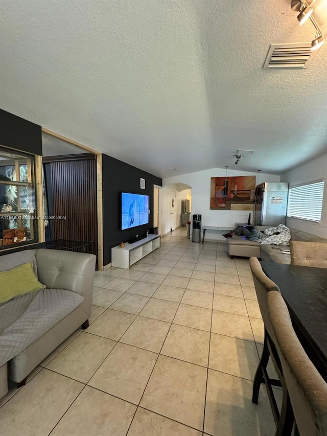 tiled living room featuring a textured ceiling and lofted ceiling