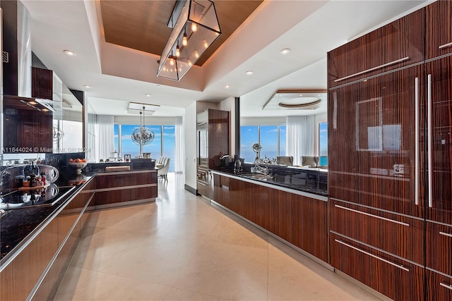 kitchen featuring light tile patterned floors, sink, decorative light fixtures, and a tray ceiling