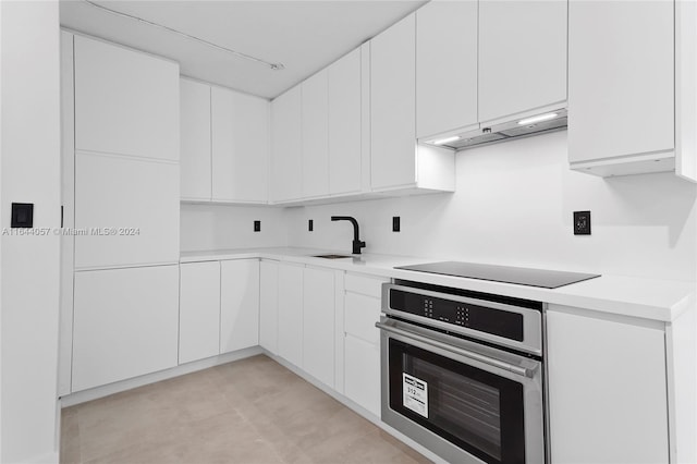 kitchen with white cabinets, oven, and range hood