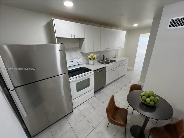 kitchen featuring tasteful backsplash, white cabinetry, appliances with stainless steel finishes, light tile patterned floors, and sink