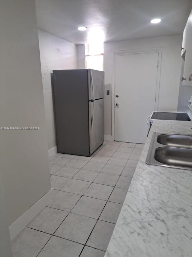 kitchen with sink, stainless steel refrigerator, range, and light tile patterned flooring