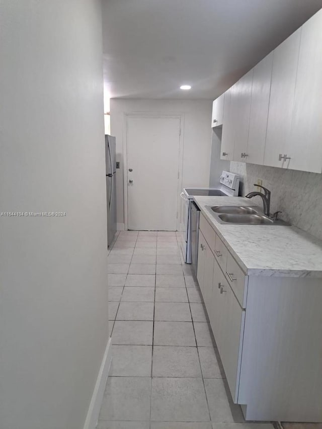 kitchen featuring sink, stainless steel fridge, electric range, and light tile patterned floors