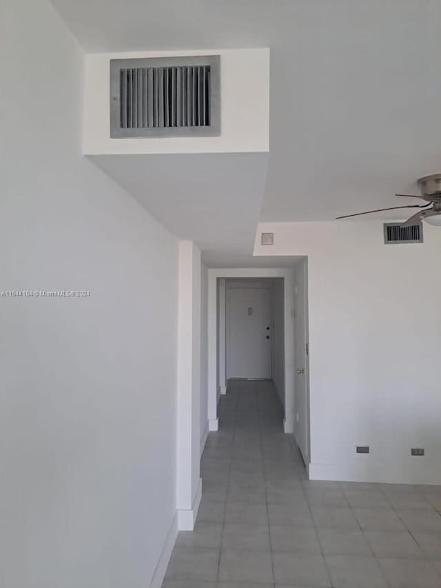 hall with light tile patterned floors, baseboards, and visible vents