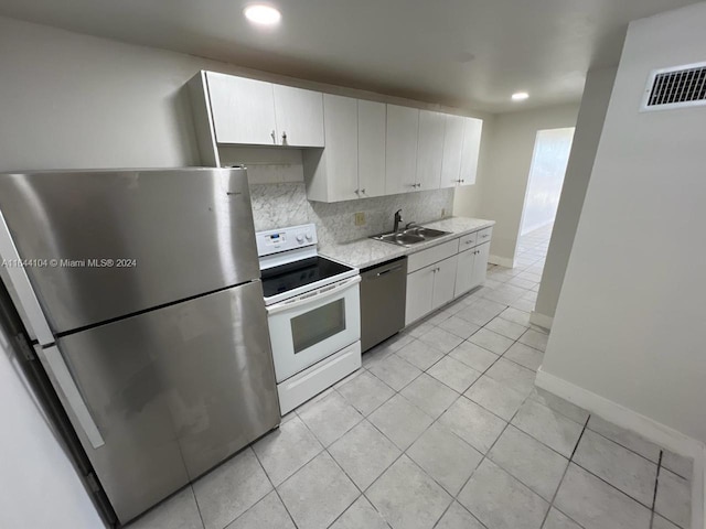 kitchen featuring light tile patterned flooring, backsplash, sink, white cabinetry, and stainless steel appliances