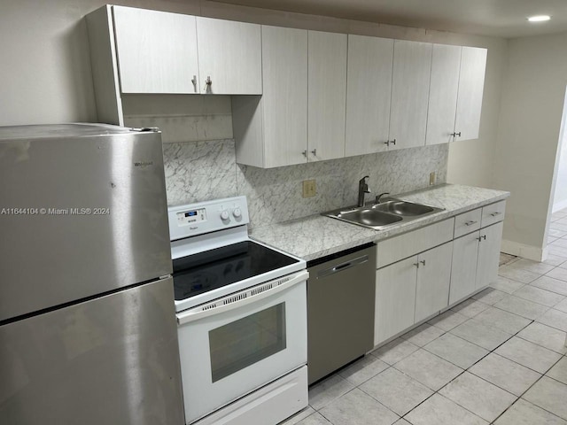 kitchen with light tile patterned flooring, appliances with stainless steel finishes, sink, and decorative backsplash