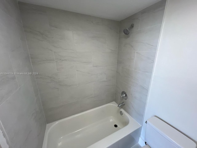 bathroom featuring toilet and tiled shower / bath