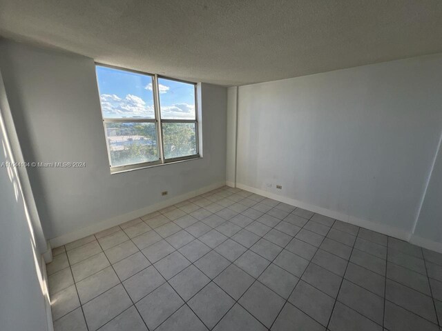 empty room featuring light tile patterned floors and a textured ceiling