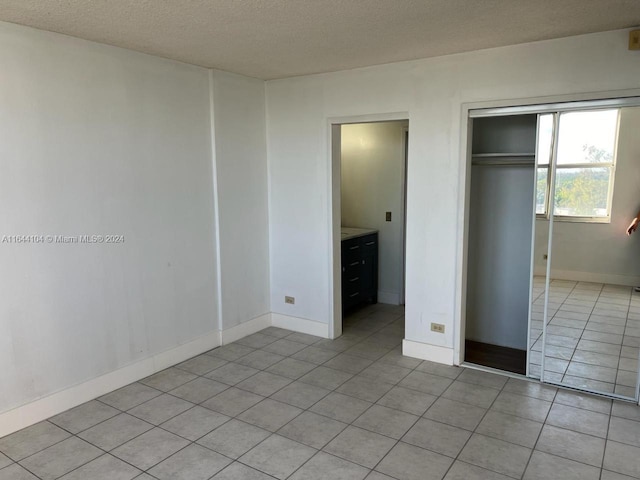 unfurnished bedroom featuring a closet, a textured ceiling, and light tile patterned floors