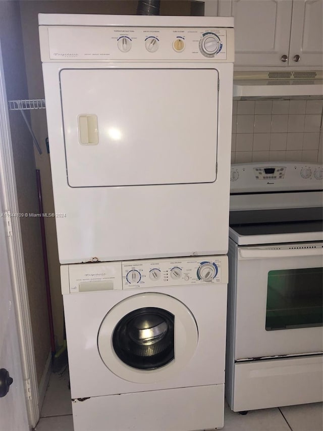 laundry area with light tile patterned floors and stacked washer and dryer