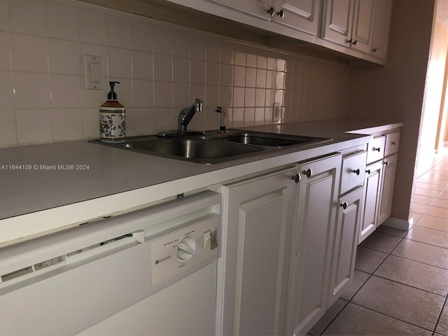 kitchen featuring tasteful backsplash, sink, white cabinets, light tile patterned floors, and white dishwasher