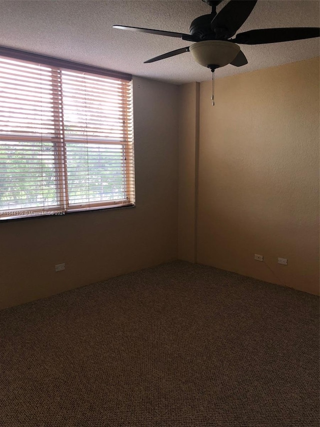 spare room with a textured ceiling, carpet flooring, and ceiling fan