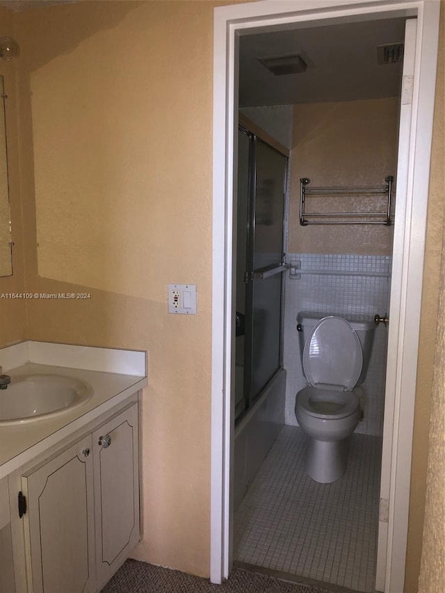 full bathroom featuring shower / bath combination with glass door, tile patterned flooring, toilet, and vanity