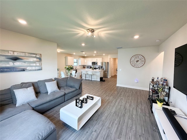 living area featuring baseboards, wood finished floors, and recessed lighting