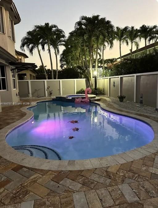 pool at dusk featuring a patio