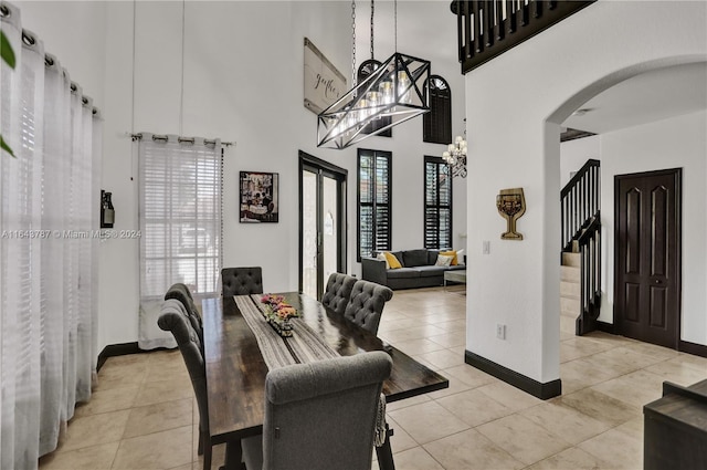 tiled dining area featuring a chandelier and a towering ceiling