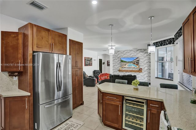 kitchen featuring wine cooler, light stone counters, decorative light fixtures, and stainless steel refrigerator