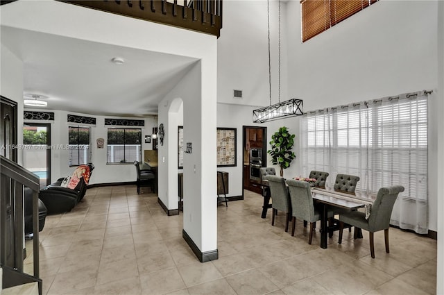 dining space featuring a towering ceiling and light tile patterned flooring