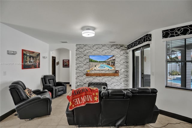 home theater featuring light tile patterned floors and a brick fireplace