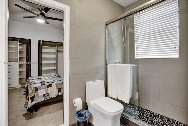 bathroom featuring ceiling fan, a shower with shower door, tile walls, and toilet