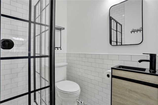 bathroom featuring tiled shower, vanity, toilet, and tile walls