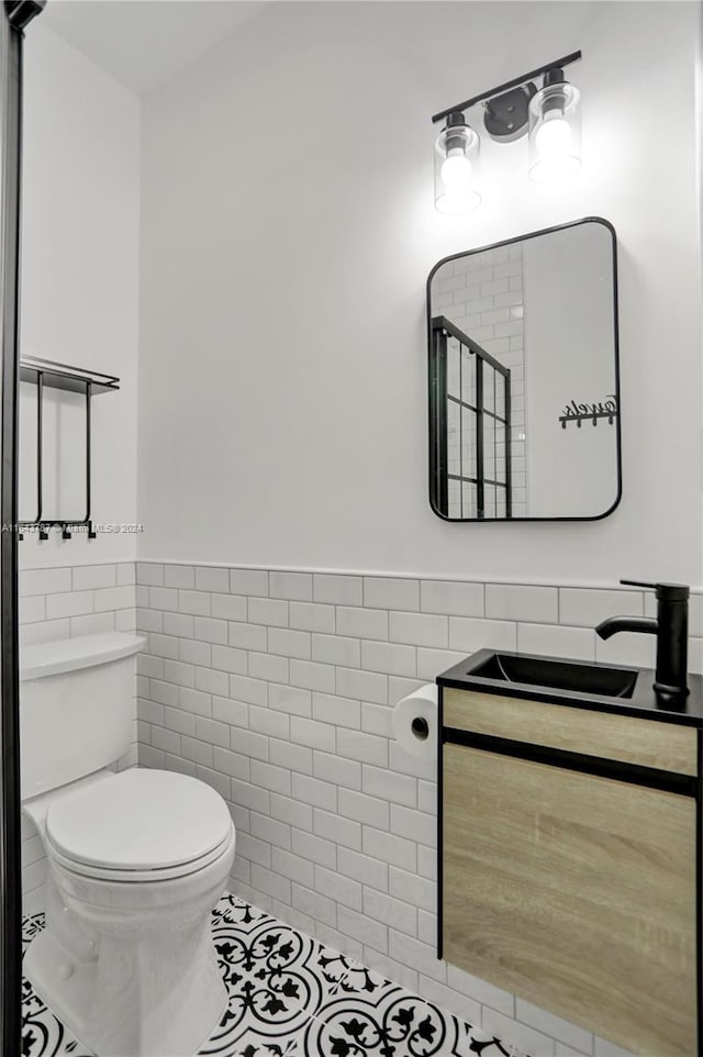 bathroom with tile patterned floors, vanity, tile walls, and toilet