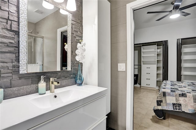 bathroom featuring vanity, a shower with door, tile patterned floors, ceiling fan, and tasteful backsplash