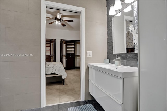 bathroom with tile patterned flooring, vanity, tile walls, and ceiling fan