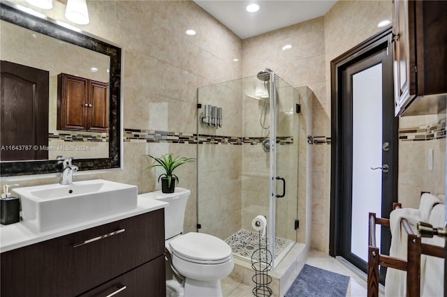 bathroom with tile patterned flooring, vanity, a shower with door, and tile walls