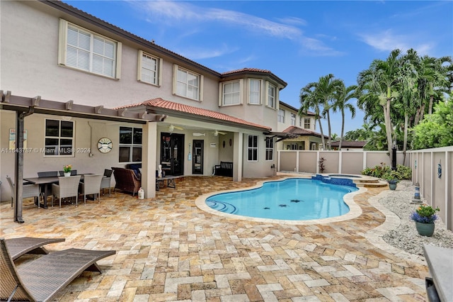 rear view of house featuring ceiling fan, a patio area, and a pool with hot tub