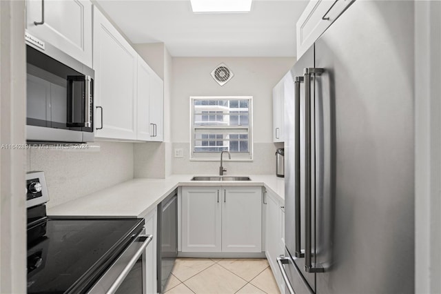 kitchen with appliances with stainless steel finishes, white cabinetry, tasteful backsplash, sink, and light tile patterned floors