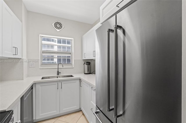 kitchen with sink, white cabinetry, light tile patterned floors, and high end fridge