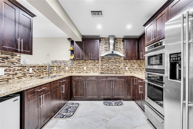 kitchen with decorative backsplash, appliances with stainless steel finishes, light stone counters, and custom range hood