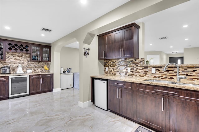 kitchen with sink, decorative backsplash, wine cooler, and light stone counters