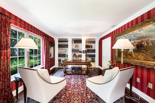 sitting room featuring baseboards, visible vents, wood finished floors, and ornamental molding