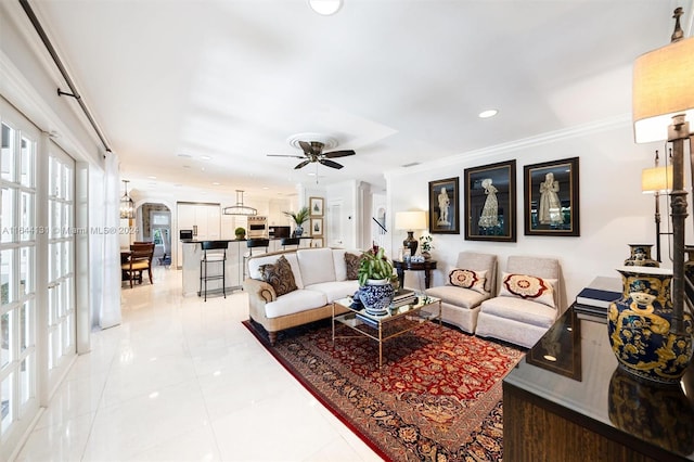 living area featuring light tile patterned floors, arched walkways, a ceiling fan, ornamental molding, and recessed lighting