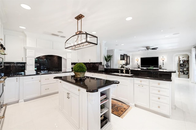 kitchen with arched walkways, a peninsula, a sink, white cabinets, and tasteful backsplash