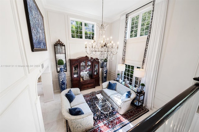 living room with a wealth of natural light, a decorative wall, crown molding, and an inviting chandelier