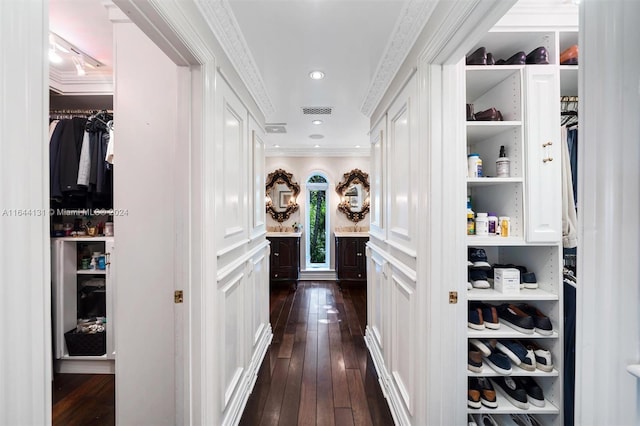 hallway featuring a decorative wall, a wainscoted wall, visible vents, ornamental molding, and dark wood finished floors