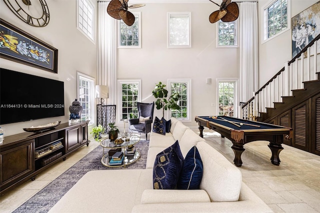 playroom with a wealth of natural light, pool table, a towering ceiling, and stone tile floors