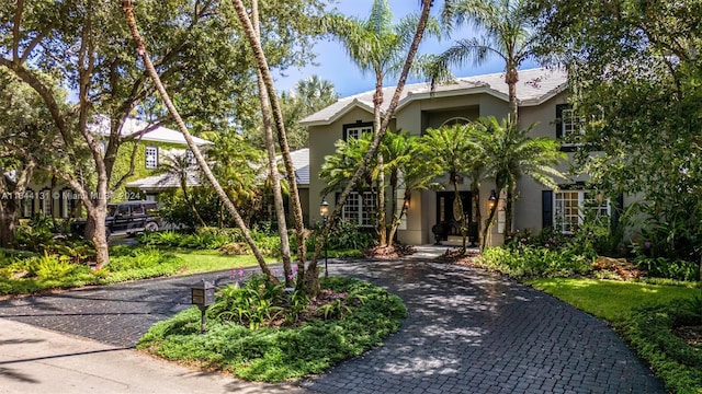 view of front of house with a tile roof, decorative driveway, and stucco siding