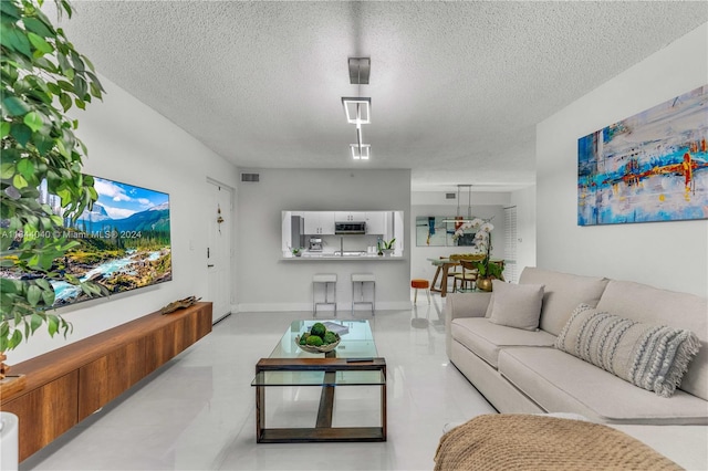 living room with a textured ceiling and light tile patterned floors