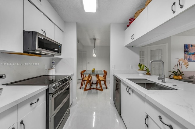 kitchen featuring white cabinets, hanging light fixtures, appliances with stainless steel finishes, and light stone counters