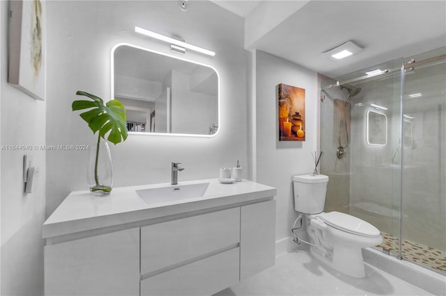 bathroom with tile patterned floors, a shower with door, vanity, and toilet