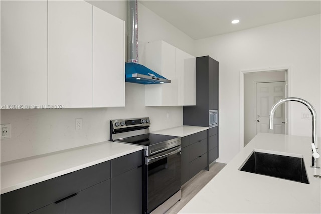 kitchen featuring light hardwood / wood-style flooring, electric stove, wall chimney exhaust hood, white cabinetry, and sink