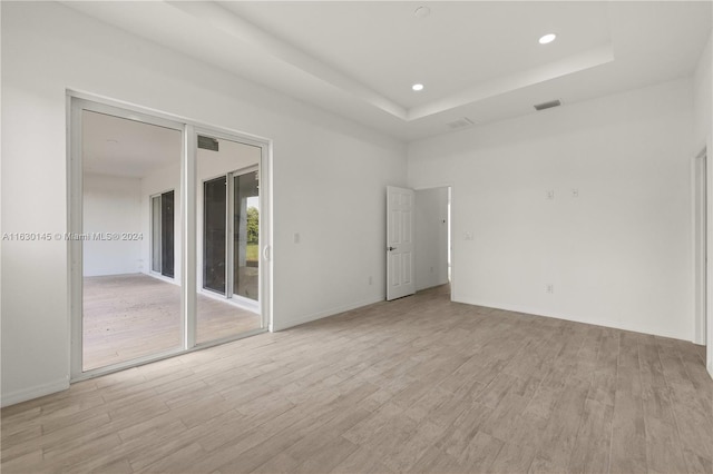 empty room featuring light hardwood / wood-style floors and a raised ceiling