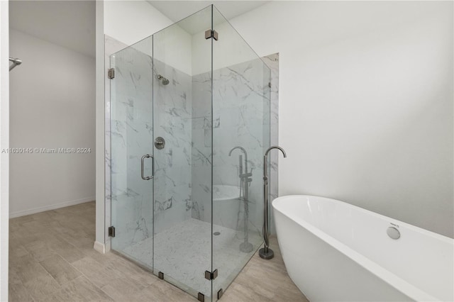 bathroom with independent shower and bath and hardwood / wood-style flooring